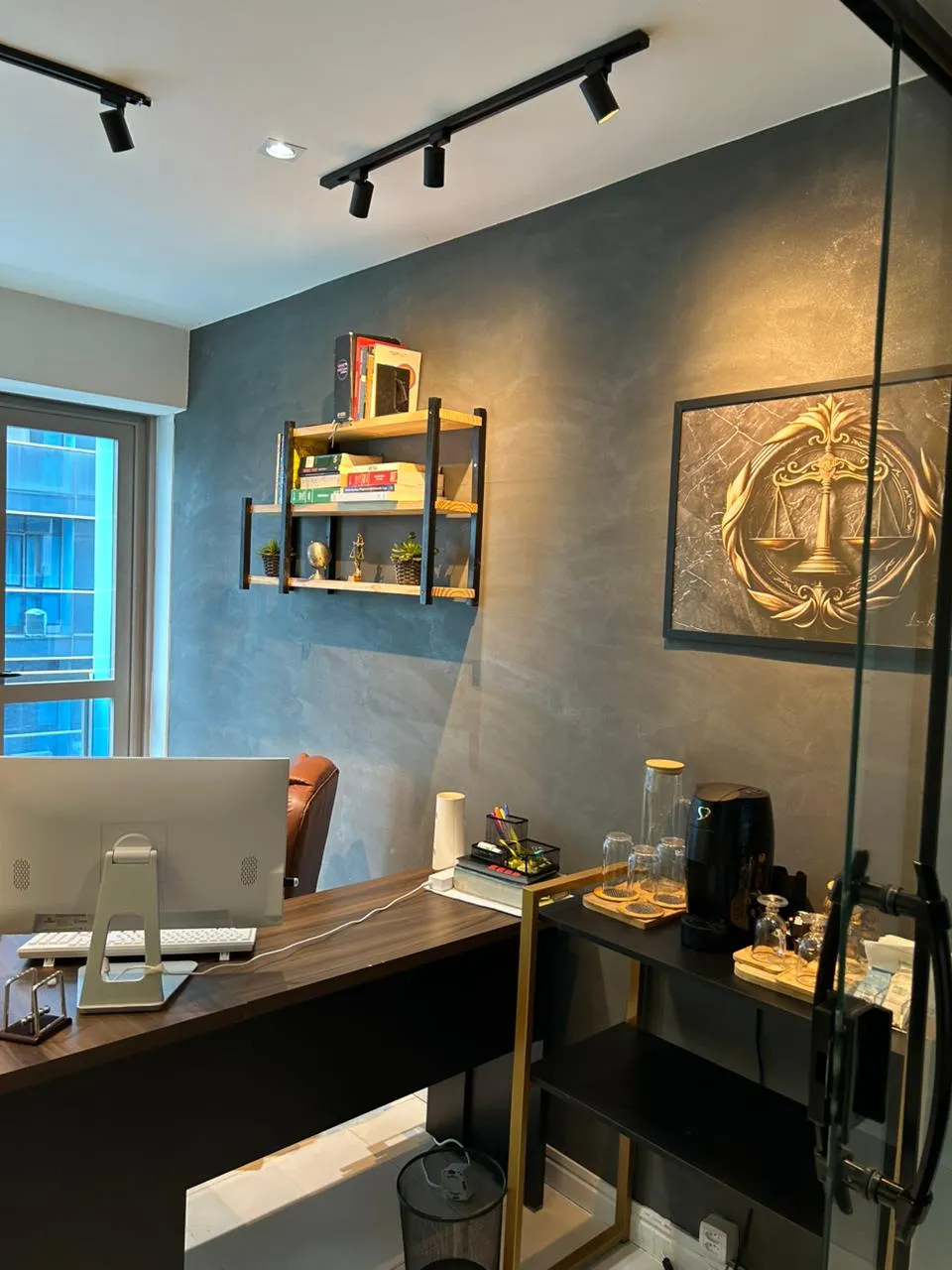 Interior do escritório MD Advocacia RJ com parede de cimento queimado, mesa executiva e arte dourada jurídica